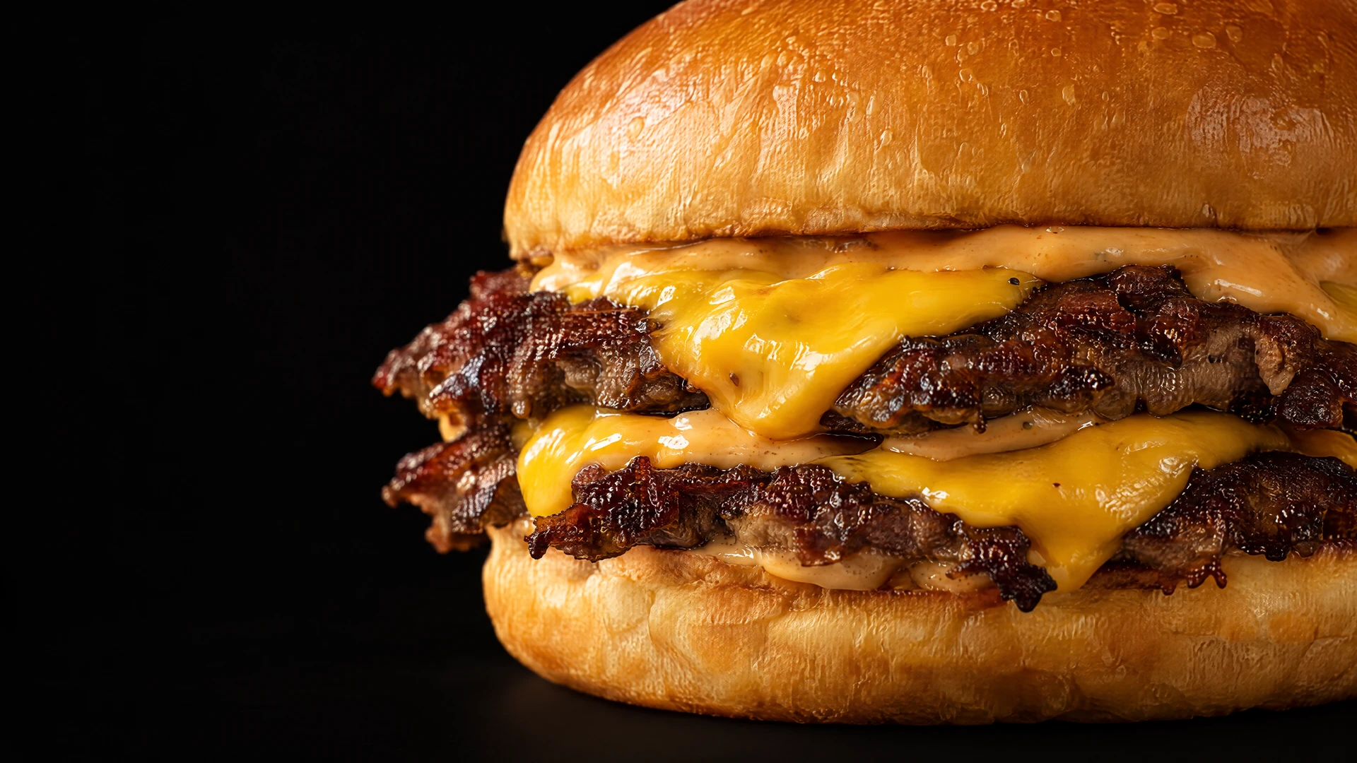 Double smash burger, bun doré, Sauce SF et fromage fondant sur fond noir